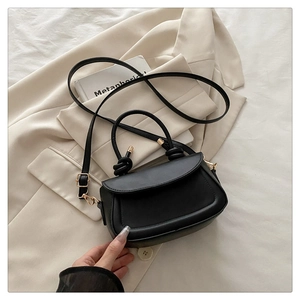 Detail of the elegant black matte leather handbag with golden hardware and knot handle design