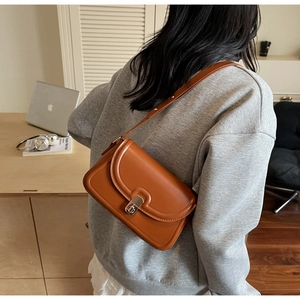Détail d'un sac porté épaule en cuir marron avec fermoir métallique en situation réelle