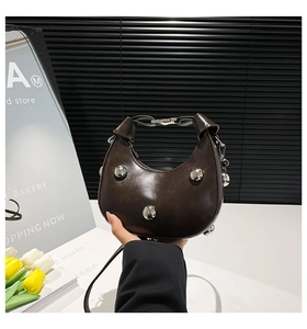 Détail du sac croissant marron foncé avec rivets argentés et bandoulière réglable