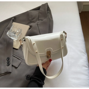 Détail du sac à bandoulière en cuir blanc avec fermoir tournant doré et rivets