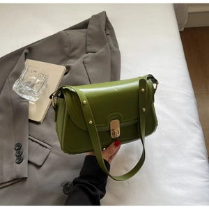 Détail du sac vintage vert avocat avec fermoir doré sur une literie blanche épurée
