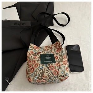 Detailed macro view of floral jacquard fabric tote bag with vintage embroidery and green label