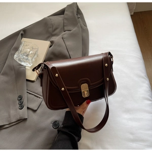 Détail du sac en similicuir marron foncé avec fermoir doré et rivets sur la bandoulière