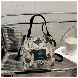 Detailed view of floral canvas tote bag with butterfly patterns on a metal shelf