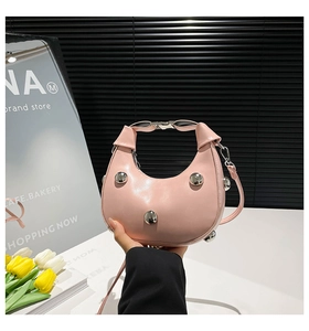 Détail du sac croissant rose avec clous argentés et poignée à boucle métallique
