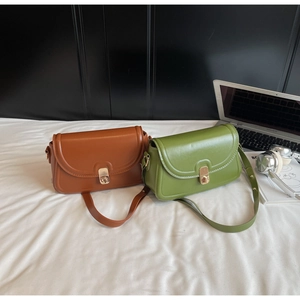 Détail de sacs à bandoulière en cuir caramel et vert avec fermoirs rotatifs en métal