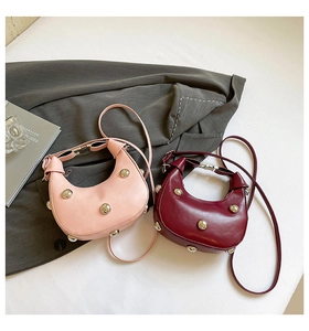 Gros plan de sacs demi-lune rose et bordeaux ornés de rivets argentés tendance