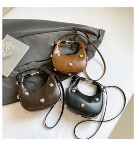 Trois sacs demi-lune cloutés en caramel et noir avec rivets argentés sur fond gris chic