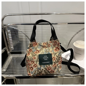 Detail of floral canvas tote bag showing the green woven label and black handle strap