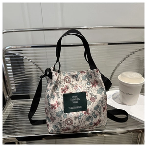 Detail of floral canvas tote bag with adjustable shoulder strap and green woven label