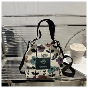 Detail of floral canvas tote bag featuring green leather logo and black woven handles