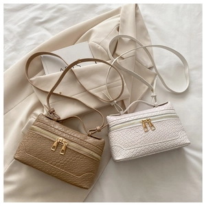 Detail of woven texture and dual gold zippers on khaki and white box bags