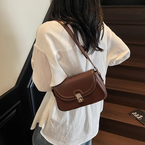 Sac bandoulière minimaliste marron foncé vintage avec fermoir doré sur un mannequin