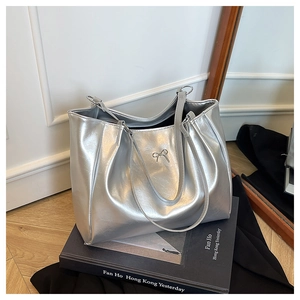 Détail du sac cabas argenté avec texture cuir et boucle métallique en forme de nœud