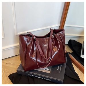 Vue détaillée d'un sac cabas rouge foncé avec nœud en métal argenté et cuir ciré texturé