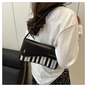 Detail of piano key design shoulder bag with golden clef metal ornament and lettering