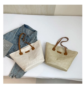 Detail of woven straw tote bags in beige and coffee colors with leather handles