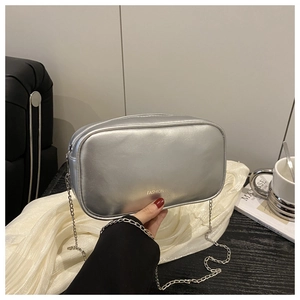 Gros plan sur la texture argentée et la bandoulière chaîne du sac élégant