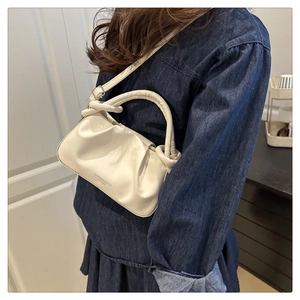 Detail of cream pleated cloud bag featuring knotted handle and San Sherman logo lettering