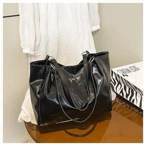 Détail du grand sac cabas en simili cuir verni noir avec un nœud métallique argenté