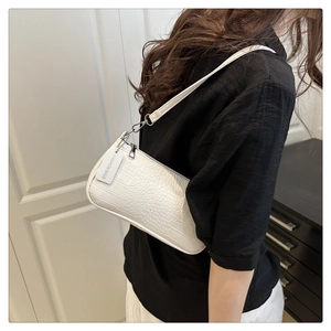 Detail of white crocodile pattern shoulder bag featuring silver metal zipper and brand tag