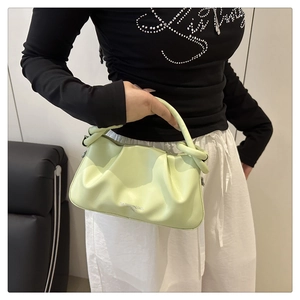 Detail of mint green square bag showing knotted handle and ruched leather texture