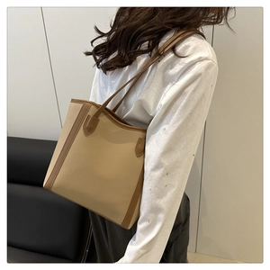 Detailed view of the large beige and brown PU leather tote bag worn by a model