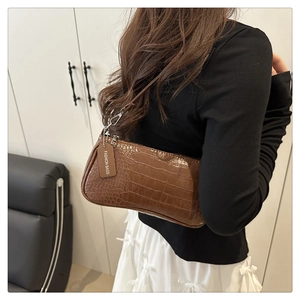 Detail shot of brown crocodile pattern on leather shoulder bag with a fashion tag