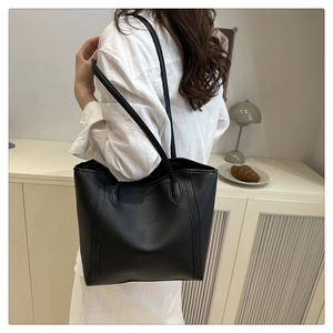 Close-up of a black large capacity PU leather tote bag worn on shoulder for commuting