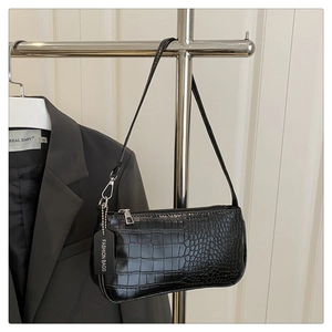 Detail of crocodile pattern baguette bag with silver zipper and fashion tag on hanger