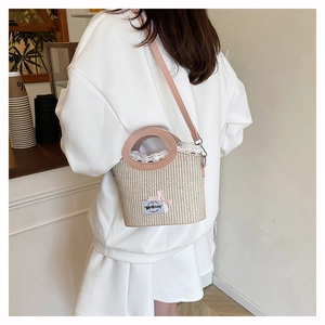 Detail of straw woven bucket bag featuring pink ribbon bow and delicate lace trim