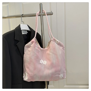 Detail of pink organza tote bag with 3D white floral embroidery hanging on a door