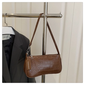 Detailed close-up of brown crocodile pattern texture and fashion tag on the baguette bag
