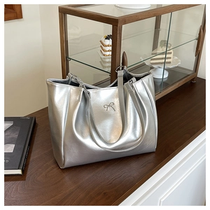 Gros plan du sac cabas argenté avec un nœud métallique décoratif et une texture de cuir brillant