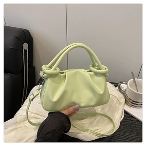 Détail du sac à main plissé vert clair avec poignée ronde et logo de marque argenté