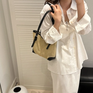 Hollow straw tote bag with black leather straps and trim for summer beach vacation