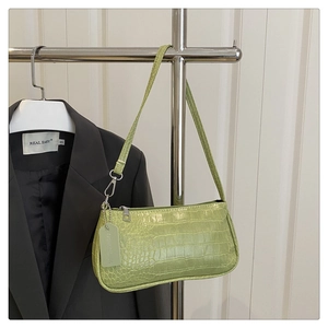 Close-up of light green crocodile embossed texture and fashion tag on the baguette bag