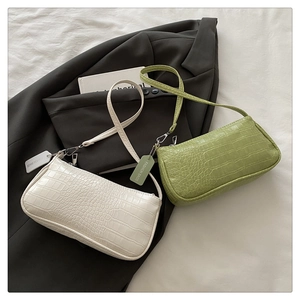 Close-up of crocodile pattern texture on cream and green baguette shoulder bags