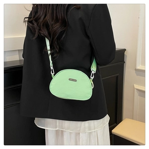 Lifestyle view of light green nylon crescent crossbody bag with white resin buckles