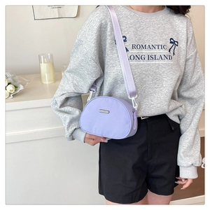 Close-up of light purple nylon crossbody bag with adjustable strap and metal logo detail