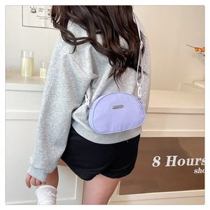 Close-up of a light purple nylon crossbody bag featuring white adjustable straps and buckle