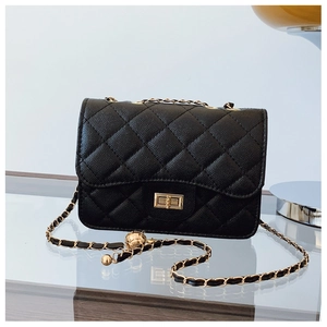 Close-up of black quilted leather texture and gold metal turn-lock on a chain crossbody bag