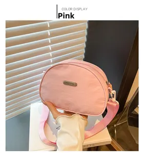 Detail view of pink Oxford fabric shell bag featuring JING PIN metal tag and wide strap