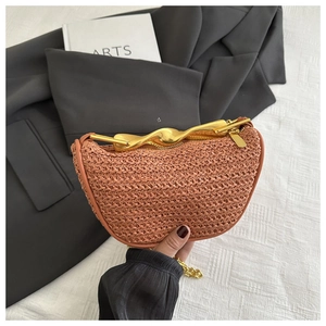 Détail du sac tressé rose corail avec poignée en métal doré et chaîne élégante