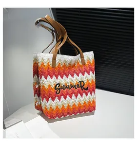 Detail der Sommer-Strohtasche mit orangefarbenem Wellenmuster und Summer-Stickerei