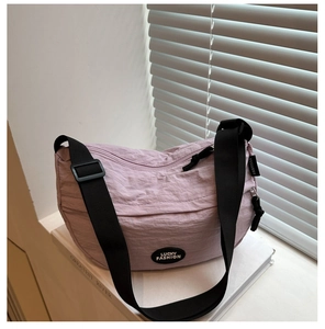 Detail of light purple crescent bag with adjustable strap on a minimalist white backdrop