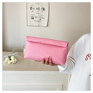 Pink woven leather envelope clutch bag held by model showing intricate craft detail