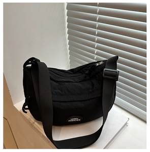 Detail of black nylon crossbody bag featuring Lucky Fashion tag and adjustable wide strap