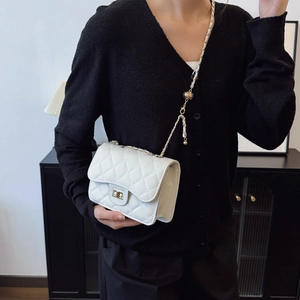 Chic white quilted leather flap bag with gold chain strap and turn-lock on a model