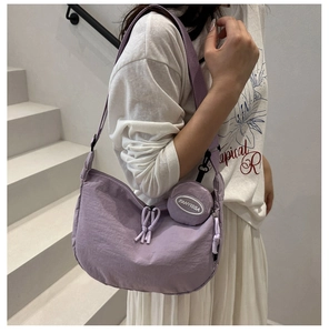 Detailed side view of purple nylon crescent tote bag worn by model on stairs